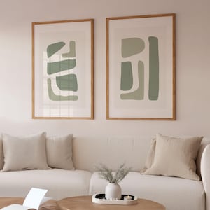 May include: Two framed abstract art prints with a minimalist design featuring geometric shapes in shades of green on a white background.