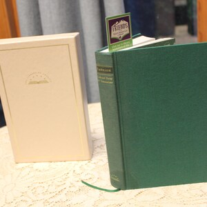 May include: A green hardcover book with a white slipcover. The book is titled "The Collected Poetry of Theodore Roethke" and has a bookmark with the word "FRIENDS" on it.