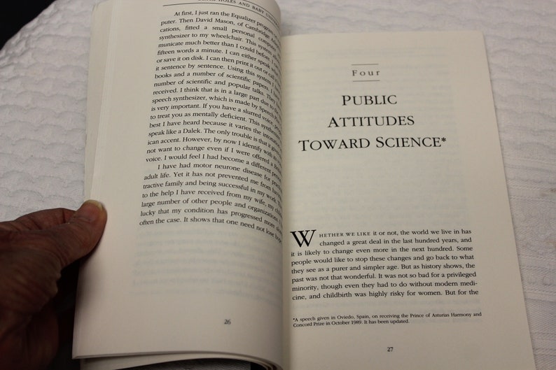 May include: A book cover with the title "Public Attitudes Toward Science" in black text on a white background. The book cover is open to a page with text about the changes in the world over the last hundred years.