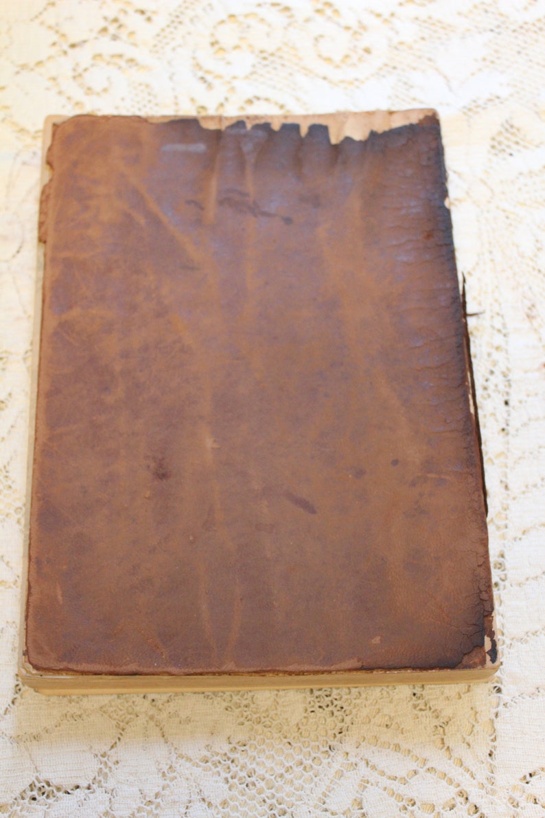 May include: A brown leather-bound book with a worn and aged appearance. The cover is smooth and has a slightly textured surface.