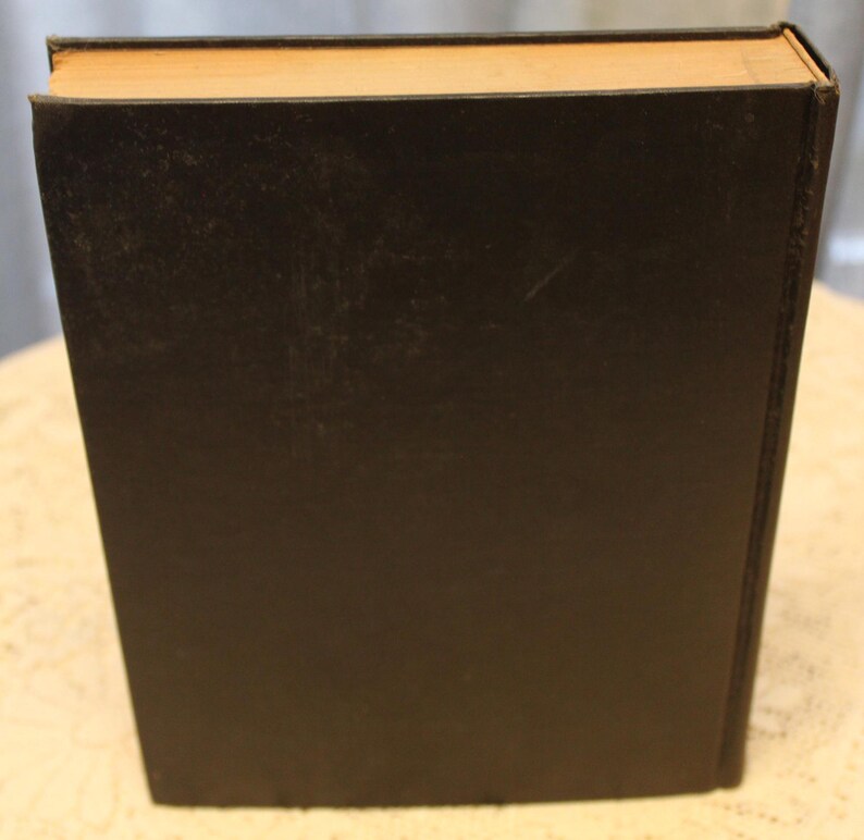 May include: A black hardcover book with a tan spine.