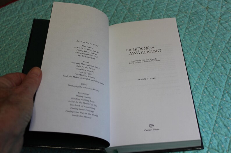 Może przedstawiać: Otwarta książka zatytułowana "The Book of Awakening" autorstwa Marka Nepo. Strony książki są białe z czarnym tekstem. Lewa strona zawiera spis treści. Prawa strona wyświetla tytuł i nazwisko autora.
