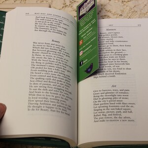 May include: An open book with green pages and a green bookmark. The book is titled "May-Day and Other Pieces" and contains poems about beauty, manners, and art. The bookmark has the word "FRIENDS" printed on it.