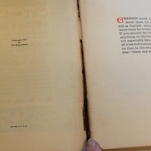 May include: A close-up of the bottom corner of a book with the text "Copyright 1927 By The Roycrofters" and "Printed in U.S.A." The right page has text that begins with "Emerson loved..."