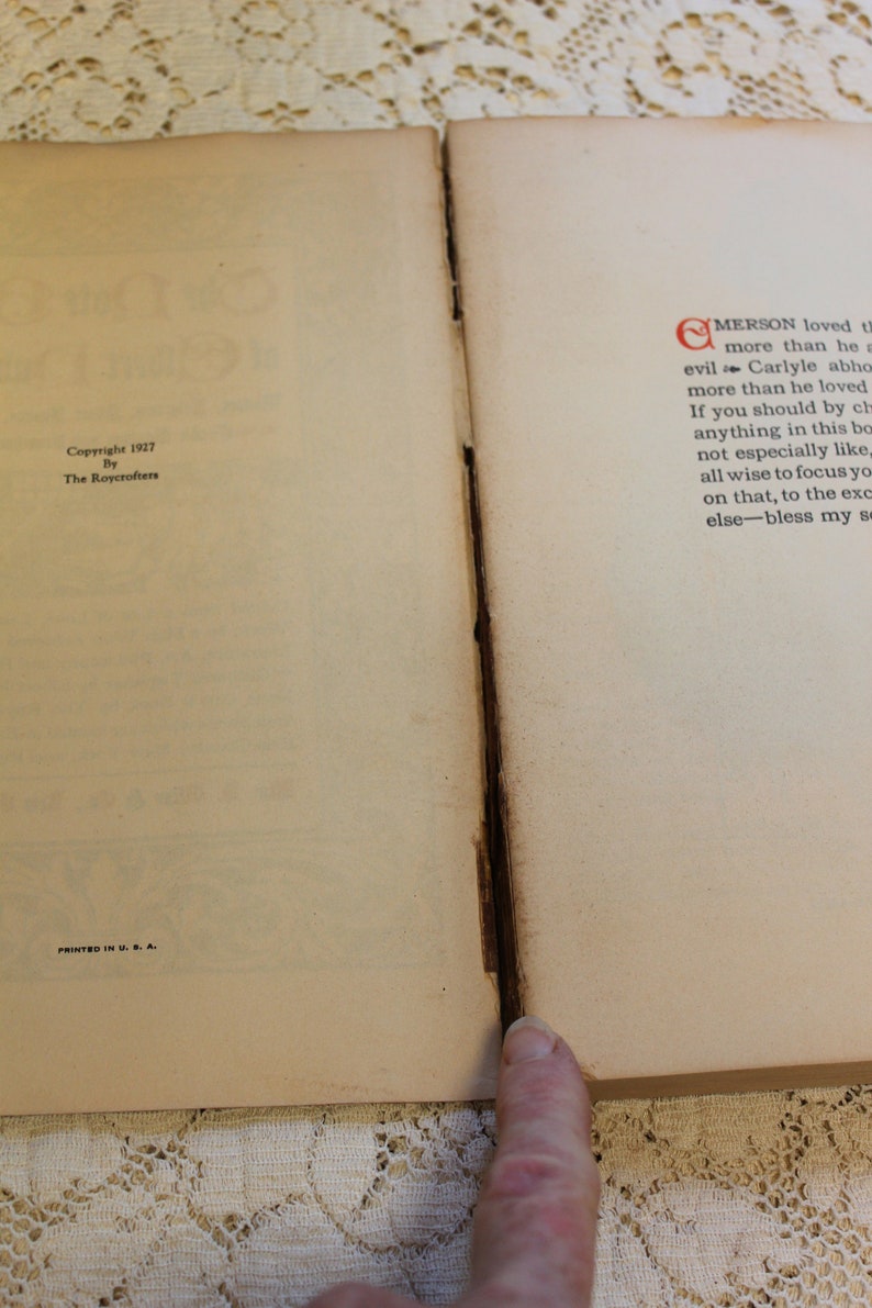 May include: A close-up of the bottom corner of a book with the text "Copyright 1927 By The Roycrofters" and "Printed in U.S.A." The right page has text that begins with "Emerson loved..."