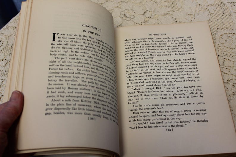 May include: A page from a vintage book titled "In the Fen" with text describing a path through a fen and a man riding a horse. The text describes the man's encounter with a creature in the fen.