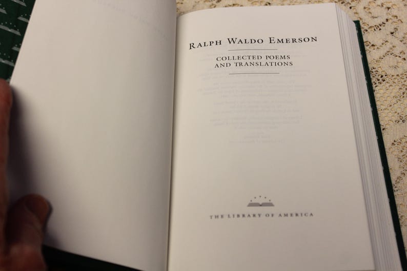 May include: An open book with a white cover and black text. The title is "Ralph Waldo Emerson Collected Poems and Translations". The book is part of "The Library of America" series.