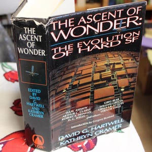 May include: A book titled "The Ascent of Wonder: The Evolution of Hard SF" with a black cover and a photo of a futuristic city on the front. The book is edited by David G. Hartwell and Kathryn Cramer and features authors such as Isaac Asimov, Arthur C. Clarke, Robert A. Heinlein, and H.G. Wells.