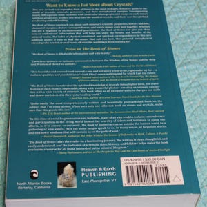 May include: A hardcover book titled "The Book of Stones" with a teal cover. The back cover features text about crystals, praise, and author names. The book is published by Heaven & Earth Publishing.