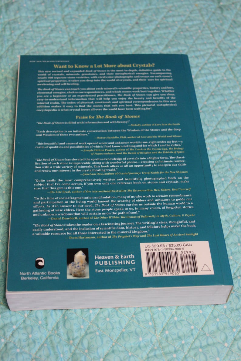 May include: A hardcover book titled "The Book of Stones" with a teal cover. The back cover features text about crystals, praise, and author names. The book is published by Heaven & Earth Publishing.