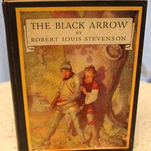 May include: The cover of a vintage book titled "The Black Arrow" by Robert Louis Stevenson. The cover features an illustration of two people in a forest setting. The people are dressed in medieval clothing and are standing near a large tree.