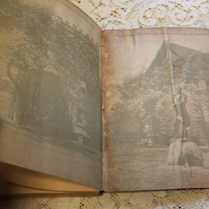 May include: An open book with two black and white photographs. The left page shows a building with trees in front of it. The right page shows a statue of a person standing on a rock with trees in the background.