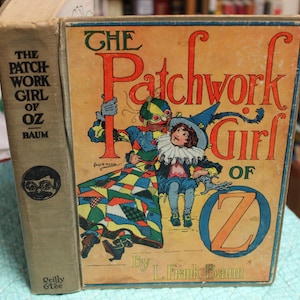 May include: A vintage copy of "The Patchwork Girl of Oz" by L. Frank Baum. The book cover features a colorful illustration of characters from the story, with the title in large, stylized letters. The spine displays the title and author's name.