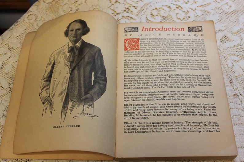 May include: A black and white portrait of Elbert Hubbard, an American author and philosopher, with the text "Introduction by Alice Hubbard" above him. The text is in a decorative font with a red star and a red crescent moon.