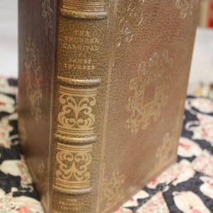 May include: A vintage hardcover book, "The Thurber Carnival" by James Thurber, in a brown leather-bound cover. The book has gold embossed decorative patterns and text on the spine. The Franklin Library is printed on the bottom of the spine.
