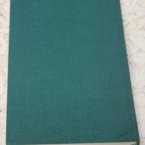 May include: A dark green hardcover book with a white spine.