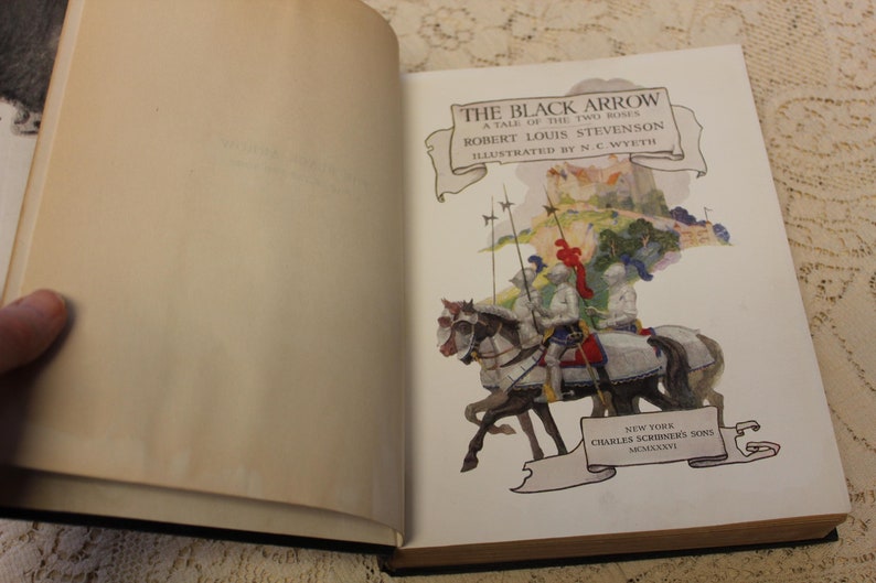 May include: An open book titled "The Black Arrow" by Robert Louis Stevenson, illustrated by N.C. Wyeth. The cover features a colorful illustration of knights on horseback riding through a forest.