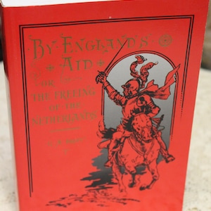 May include: Red book cover with gold lettering that reads "By England's Aid for the Freeing of the Netherlands". The cover features a black and white illustration of a knight on horseback.