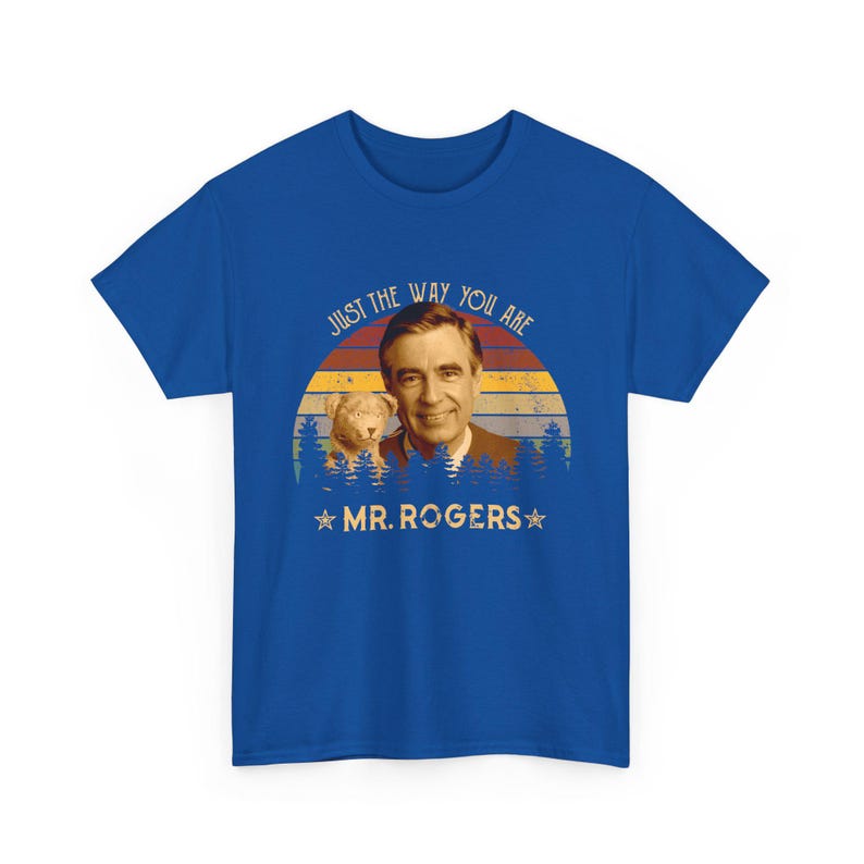 May include: A royal blue t-shirt featuring a graphic print of Mr. Rogers and a small dog. The design includes a sunset background with horizontal stripes, a forest silhouette, and the text "JUST THE WAY YOU ARE" and "MR. ROGERS" with stars.