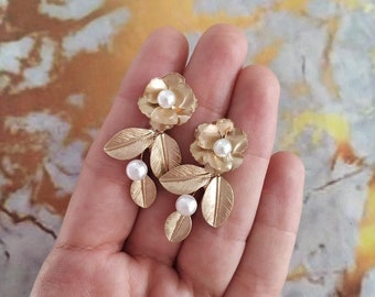 May include: Gold tone earrings with a floral design and pearl accents.