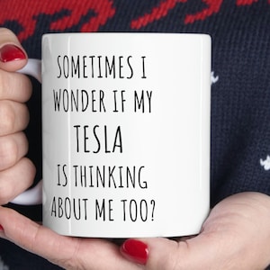 May include: White ceramic mug with black text that reads "Sometimes I wonder if my Tesla is thinking about me too?"