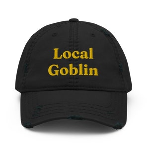 May include: Black distressed baseball cap with the text "Local Goblin" embroidered in yellow.