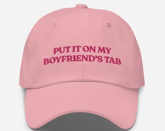 May include: Pink baseball cap with the text "PUT IT ON MY BOYFRIEND'S TAB" embroidered in pink.
