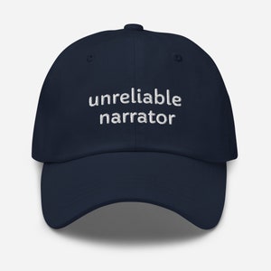 Könnte beinhalten: Eine marineblaue Baseballkappe mit weiß gesticktem Text, der "unzuverlässiger Erzähler" lautet.