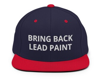 May include: A navy blue and red baseball cap with the text "BRING BACK LEAD PAINT" embroidered in white.