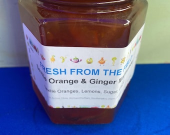 May include: A glass jar of Seville Orange & Ginger Marmalade. The jar has a gold lid and a white label with the text "FRESH FROM THE FIELD Seville Orange & Ginger Marmalade Seville Oranges, Lemons, Sugar".