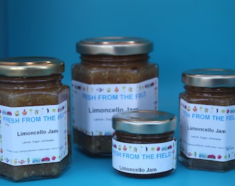 May include: Four glass jars of limoncello jam, labeled "Fresh From The Field" with a colorful design. The jars are on a blue surface.