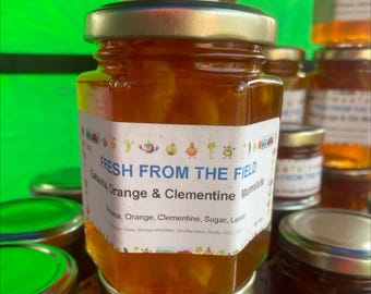 May include: A glass jar of orange and clementine marmalade with a label that reads "FRESH FROM THE FIELD Satsuma, Orange & Clementine Marmalade".
