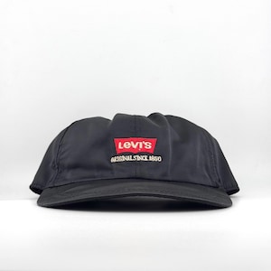 Puede incluir: Gorra de béisbol negra con el logotipo de Levi's en rojo y blanco. El texto "ORIGINAL SINCE 1850" está bordado en dorado. La gorra está hecha de un material liso, posiblemente nailon.