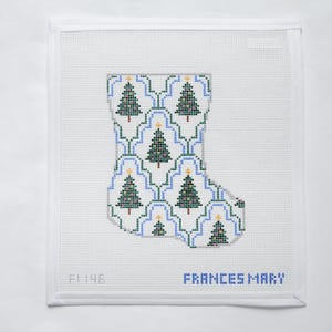 May include: A needlepoint Christmas stocking with a repeating pattern of green Christmas trees and gold stars on a white and blue background. The text "FRANCES MARY" is in blue.