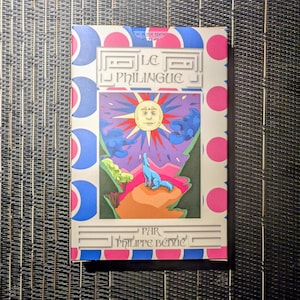 Peut inclure: Couverture de livre avec le titre "LE PHILINGUE" et le nom de l'auteur, Philippe Bénic. La couverture présente une illustration colorée d'un soleil avec un visage, un loup bleu hurlant et un paysage avec des montagnes et des nuages. La bordure a des pois roses et des formes bleues et roses.