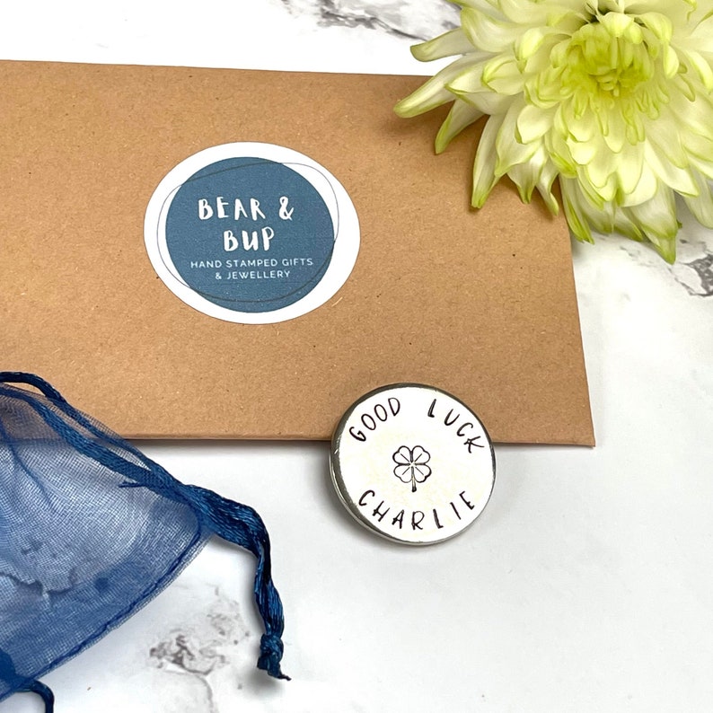 good luck aluminium pocket token with the name Charlie and a four leaf clover stamped on it in black.