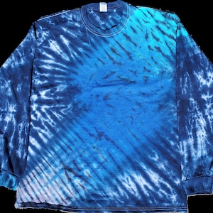 May include: A long-sleeved tie-dye shirt in shades of blue, white, and teal. The shirt has a swirling pattern with a diagonal design.