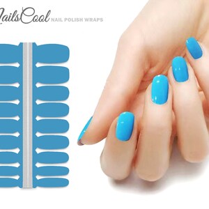 May include: A sheet of 18 blue nail polish wraps, with a silver strip down the center. The wraps are designed to fit on fingernails. A hand with blue nail polish is shown in the background.