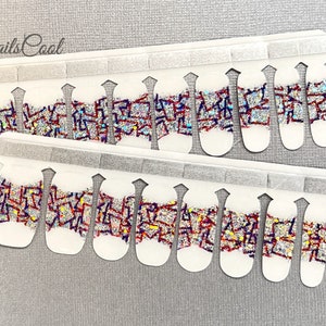 May include: Nail polish wraps with a geometric design featuring red, blue, and silver glitter on a white background. The wraps are arranged in two rows of ten on a white backing sheet.