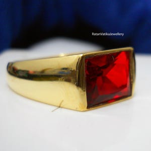 May include: A gold ring with a large, square, red gemstone.