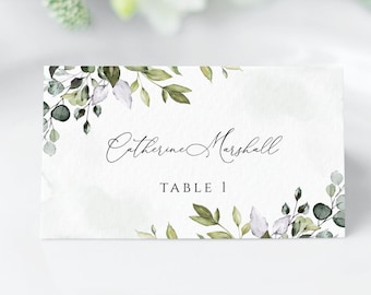 May include: White place card with green and purple watercolor floral design. The text reads "Catherine Marshall, Table 1."