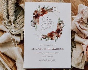 May include: Save the date card with a floral wreath design in shades of red, orange, and brown. The text reads "Save the Date" with the names Elizabeth & Marcus, the date Saturday, May 15th, 2027, and the location Paris, France.
