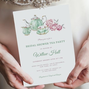 May include: A white invitation card with a green and pink watercolor illustration of a teapot and teacups. The text on the card reads "Please join us for a Bridal Shower Tea Party in honor of Willow Hall Saturday August 27th at 1 PM Soho Grand Hotel, 310 W Broadway, New York, NY 10013 RSVP to Laura by August 1st at 000-000-0000 Registered at Target and Amazon"