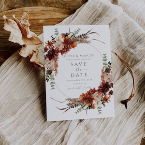 Peut inclure: Carte de sauvegarde de la date avec une couronne de fleurs dans des tons de rouge, orange et blanc. Le texte indique "Olivia & Marcus se marient. Sauvegarde de la date. 1er septembre 2028. Londres, Royaume-Uni. Invitation formelle &agrave; suivre."