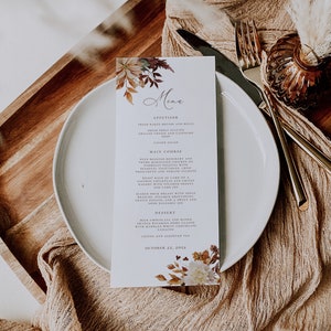 May include: A fall-themed menu card with a floral design in shades of orange, brown, and white. The menu lists appetizers, main courses, and desserts. The text on the card reads "Menu", "Appetizer", "Main Course", "Dessert", and "October 22, 2022".