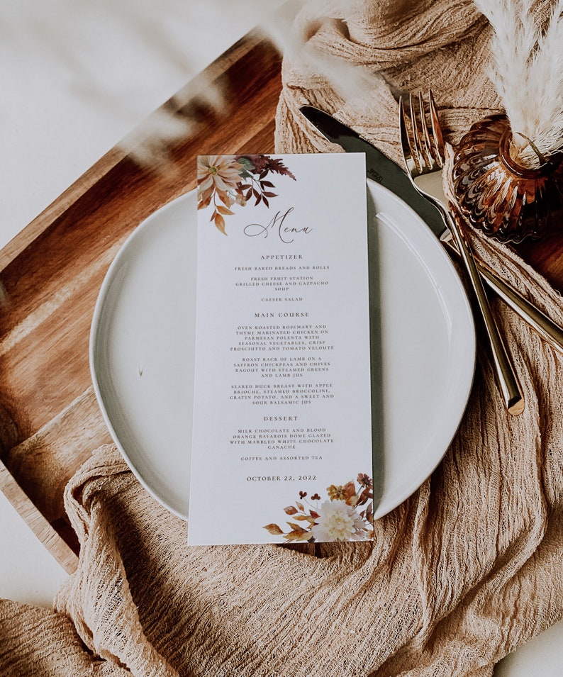 May include: A fall-themed menu card with a floral design in shades of orange, brown, and white. The menu lists appetizers, main courses, and desserts. The text on the card reads "Menu", "Appetizer", "Main Course", "Dessert", and "October 22, 2022".