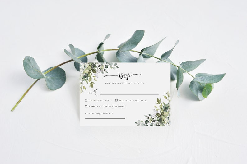 Puede incluir: Tarjeta RSVP blanca con borde floral de acuarela verde. El texto dice "RSVP" en cursiva y "Por favor, responda antes del 1 de mayo". La tarjeta tiene casillas de verificaci&oacute;n para "Acepta con gusto" y "Rechaza con pesar" y espacio para "N&uacute;mero de invitados que asistir&aacute;n" y "Requisitos diet&eacute;ticos".