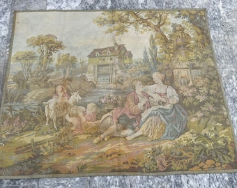 May include: A vintage tapestry depicting a pastoral scene with a couple sitting by a river, a woman tending to goats, and a small cottage in the background. The tapestry features a variety of colors, including greens, browns, and blues.