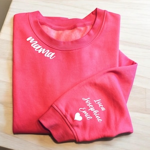 May include: A pink sweatshirt with the word "mama" embroidered on the front and the names "Luca", "Josephine", and "Emil" embroidered on the sleeve with a white heart.