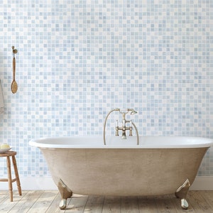 May include: A white freestanding bathtub with a chrome faucet and shower head. The bathtub is in a bathroom with a blue and white tiled wall and a wooden floor.
